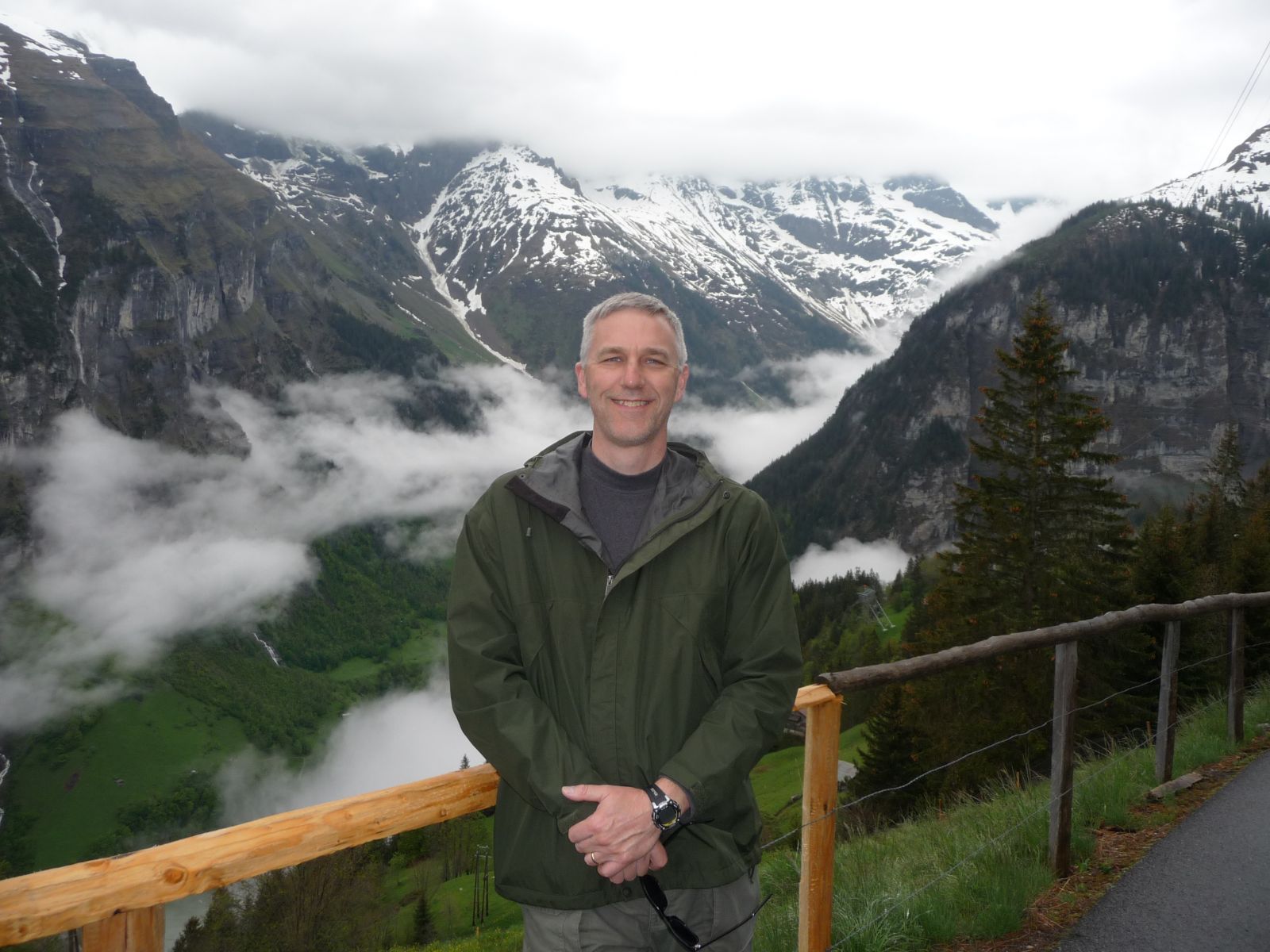 Dale smiling for a photo with cloud covered mountains in the background.